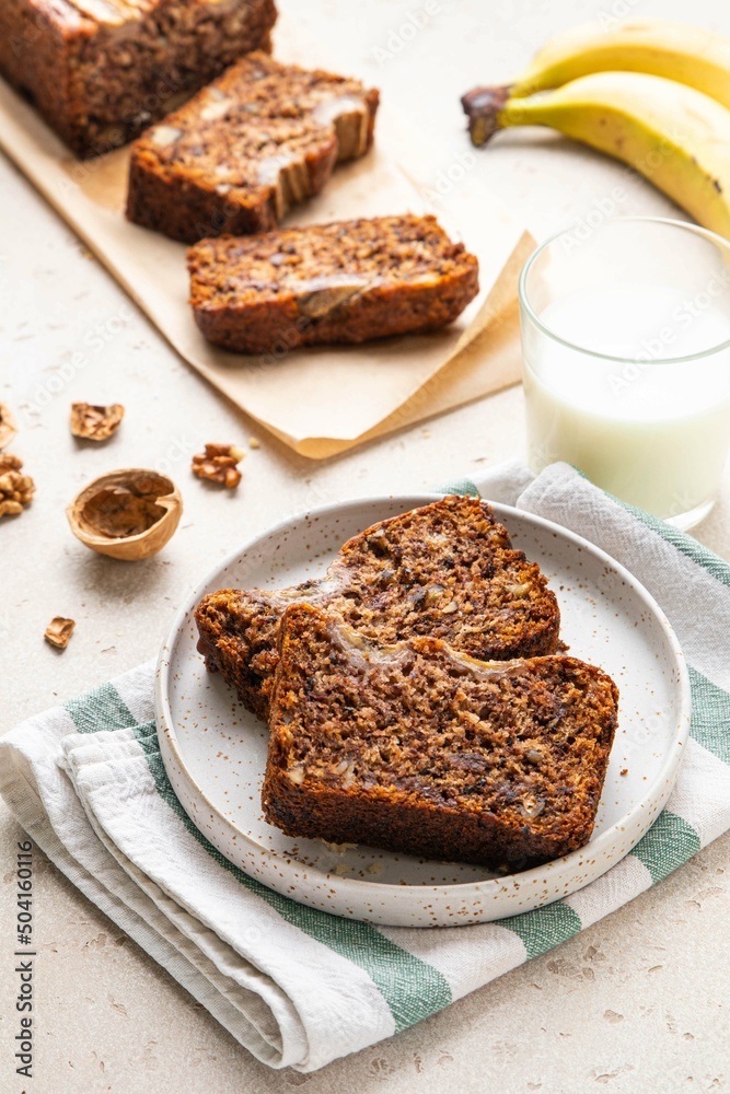 Pieces of american homemade sliced banana bread with chopped walnuts, chocolate and cinnamon on light background. Breakfast concept with milk. Vegan healthy food. Selective focus. Pieces of american homemade sliced banana bread with chopped walnuts, chocolate and cinnamon on light background. Breakfast concept with milk. Vegan healthy food. Selective focus.