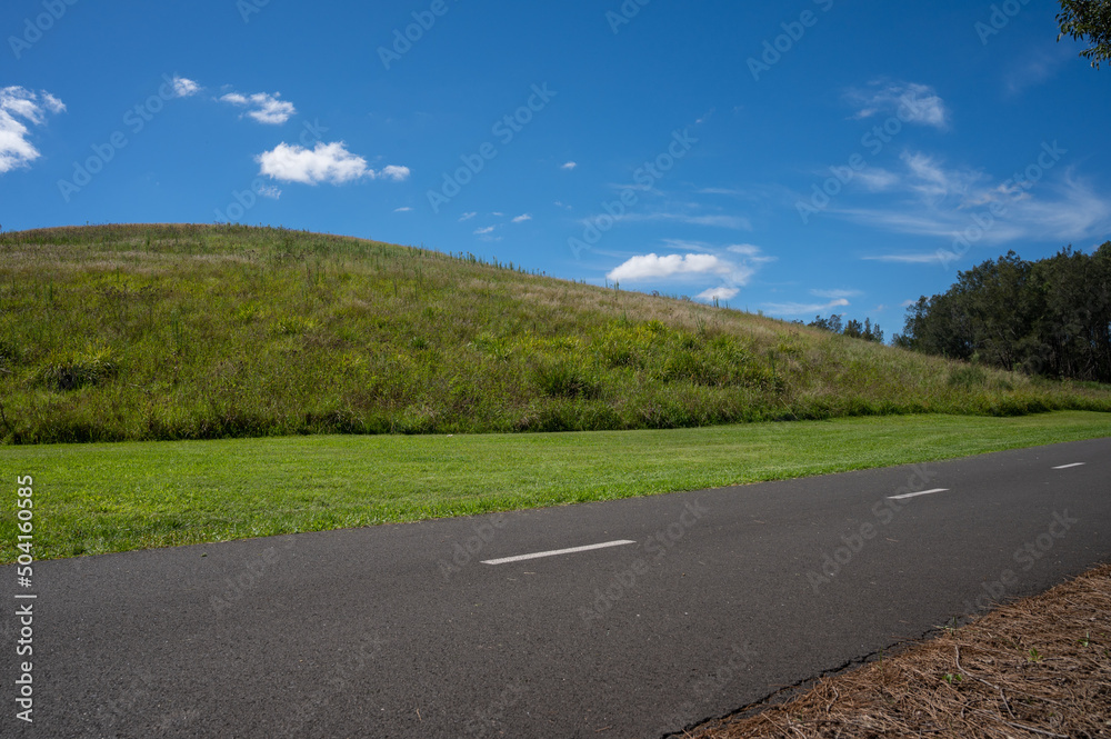 path near meadow and hill under sunny blue sky