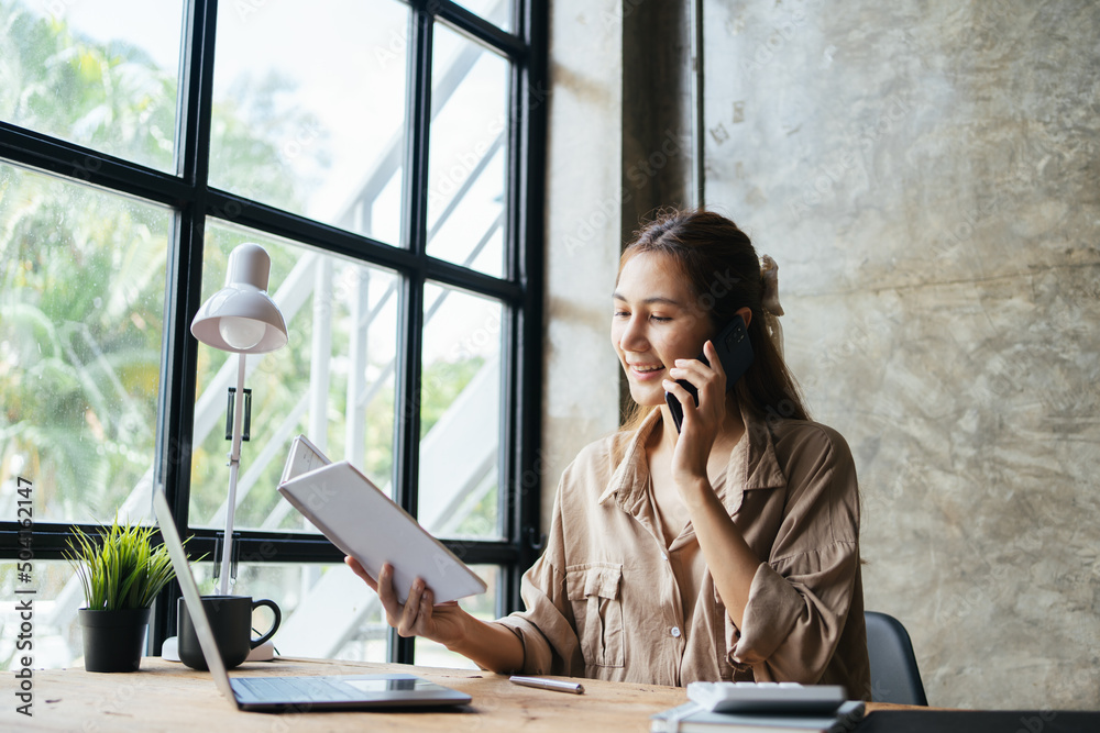© PaeGAG - Asian woman in casual clothes is happy and cheerful while communicating with her smartphone and working in a modern office.