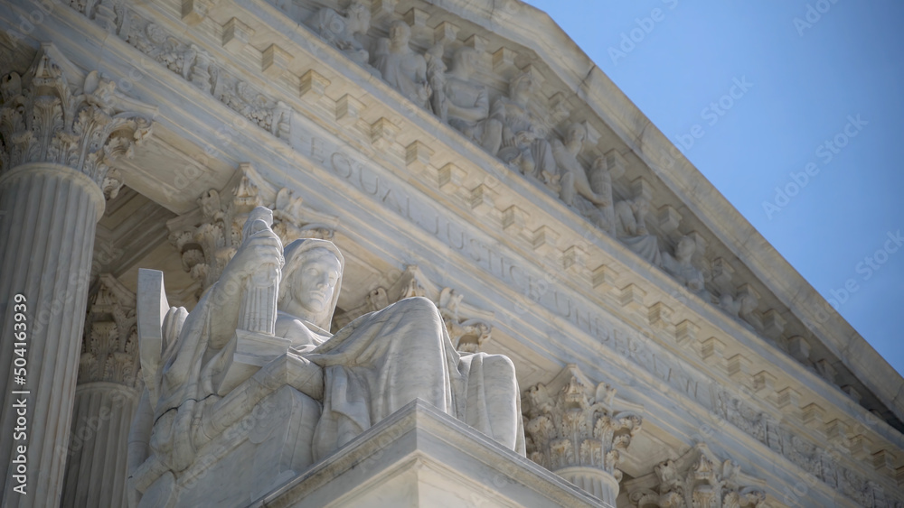 Naklejka premium Closeup of sculpture on the Supreme Court building of The Three Fates with Equal Justice slightly out of focus in the distance.