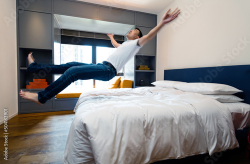 Happy man jumping to the bed photo