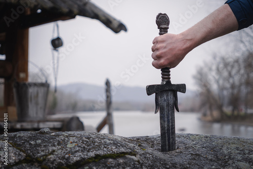 famous sword excalibur of King Arthur stuck in rock. Edged weapons from the legend Pro king Arthur. photo