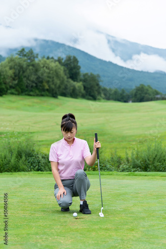 Female golfer crouching looking the golf ball