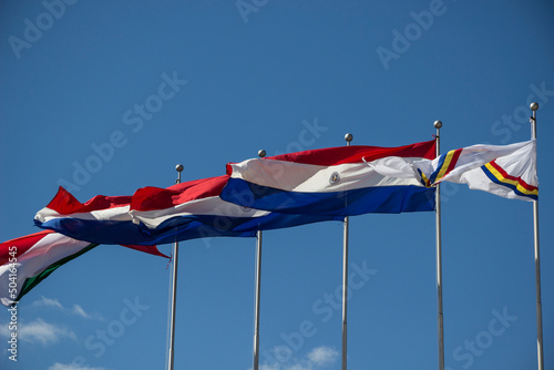 Paraguay - Itapua - Encarnacion - Waving flags of Paraguay country, Itapua department and Encarnacion city at the flagstaffs on plaza de Armas in Encarnacion photo