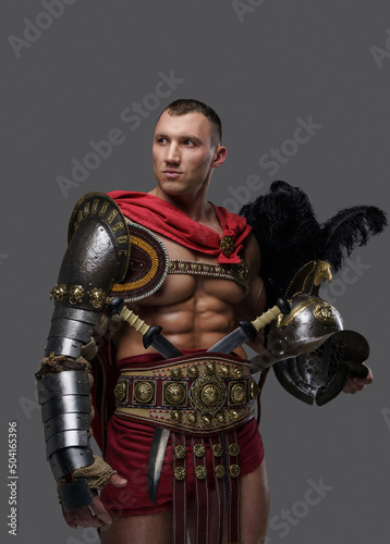 Shot of isolated on grey background roman gladiator holding plumed helmet.