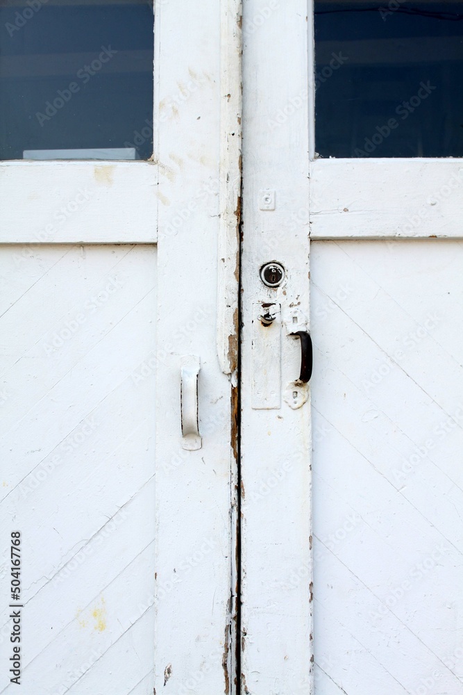 A close up detailed image of white rustic doors with metal handles.
