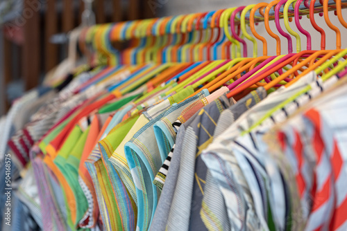 Line of multi colored clothes on wooden hangers in store. Sale