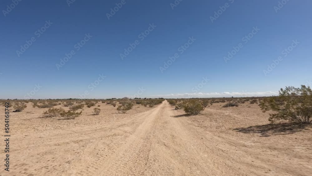 Driver point of view driving along a dirt road in the barren Mojave Desert's arid landscape Driver point of view driving along a dirt road in the barren Mojave Desert's arid landscape