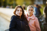 Woman posing outdoors. Portrait of mother in front of teenage daughter. Selective focus on woman.