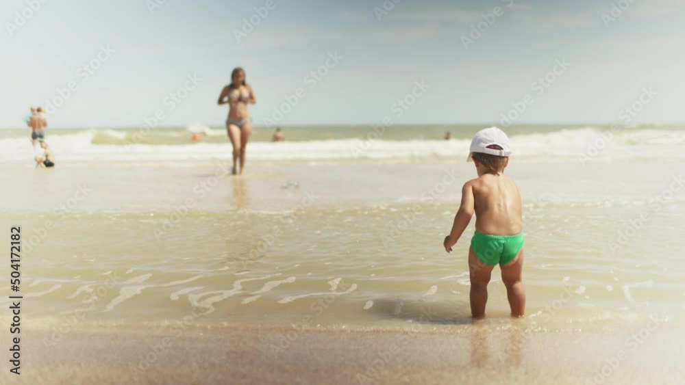 Kid collects shells and pebbles in the sea on a sandy bottom under the summer sun on a vacation Kid collects shells and pebbles in the sea on a sandy bottom under the summer sun on a vacation