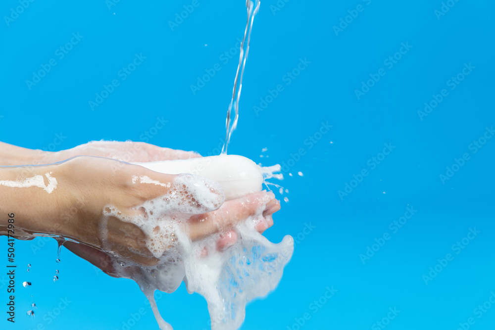 Fototapeta premium Washing hands and soap with water on blue background