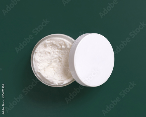 Homemade cream in plastic jar on dark green  top view. Brand packaging mockup