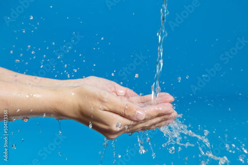 Woman hands catching water on blue background