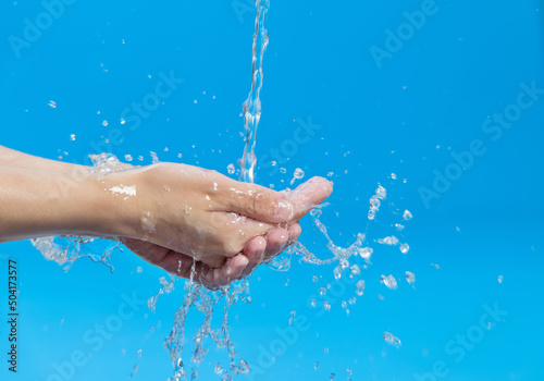 Washing hands with water on blue background