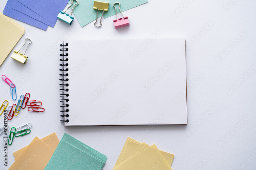 top view of blank notebook near colorful stationery on white. top view of blank notebook near colorful stationery on white.