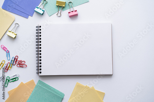 top view of blank notebook near colorful stationery on white.