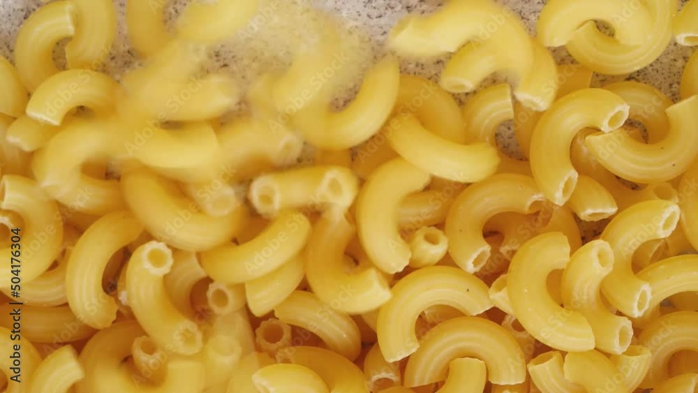Uncooked elbow macaroni slowly being poured and filling up screen bottom to top Uncooked elbow macaroni slowly being poured and filling up screen bottom to top