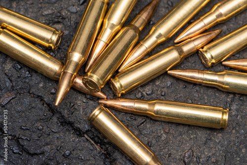 A scattering of cartridges with 7.62 caliber bullets for a Kalashnikov assault rifle on the asphalt in the city, close-up, selective focusing. Concept: the war in Ukraine, urban battles, shootout.
