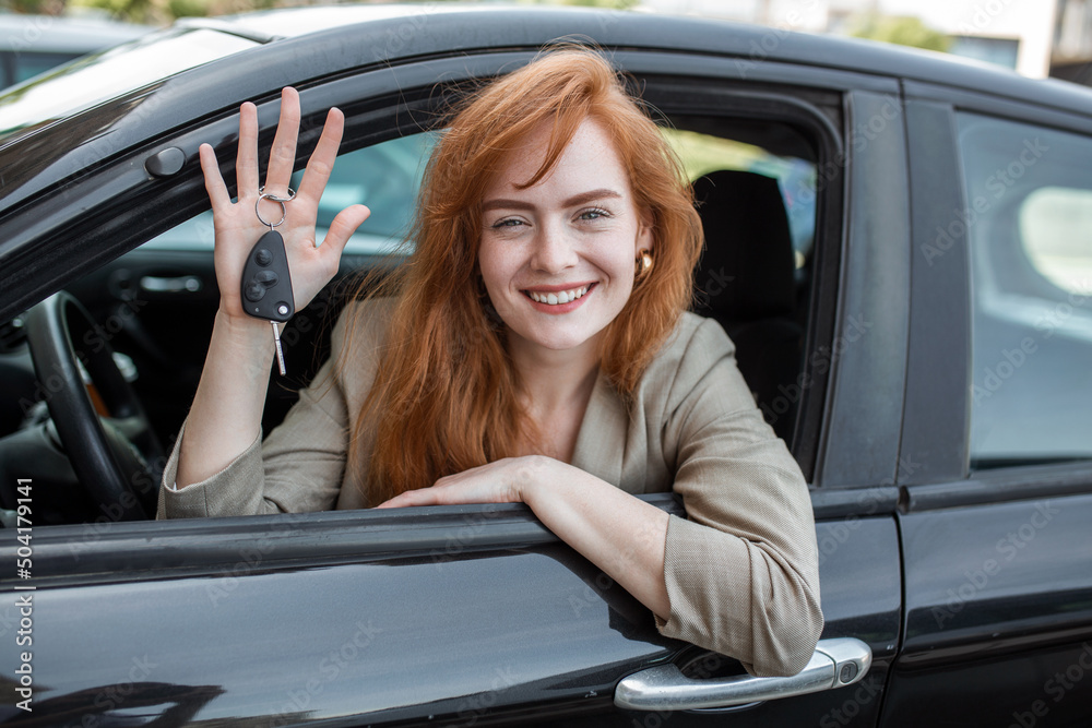 Young woman smiling showing her new car keys, keys to her rental car.