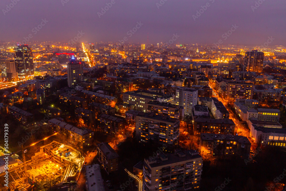 Fototapeta premium Ukraine, Kyiv – March 12, 2016: Aerial panoramic view on central part of Kyiv city from a roof of a high-rise building. Night life in a big city. Foggy and rainy weather. 