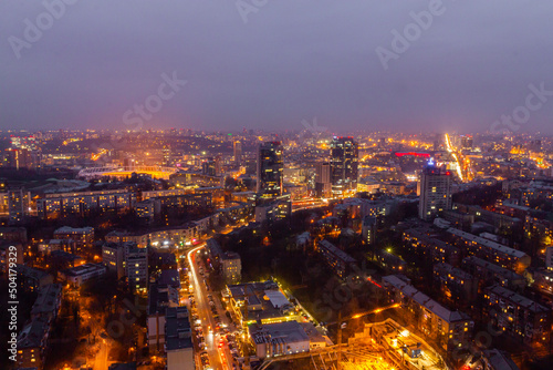 Ukraine, Kyiv – March 12, 2016: Aerial panoramic view on central part of Kyiv city from a roof of a high-rise building. Night life in a big city. Foggy and rainy weather. 