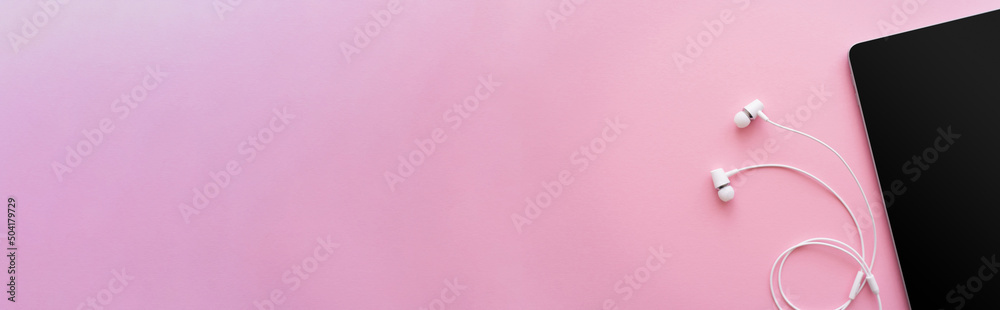 top view of digital tablet with blank screen near earphones on pink, banner. top view of digital tablet with blank screen near earphones on pink, banner.
