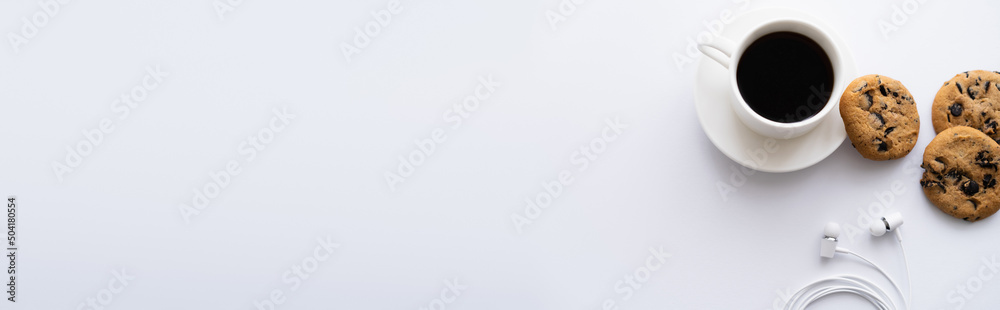 Φωτογραφία top view of cup of coffee near chocolate chip cookies and wired earphones on white, banner
