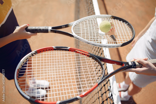 Cropped photo of two rackets and ball in hands of female tennis players © prostooleh