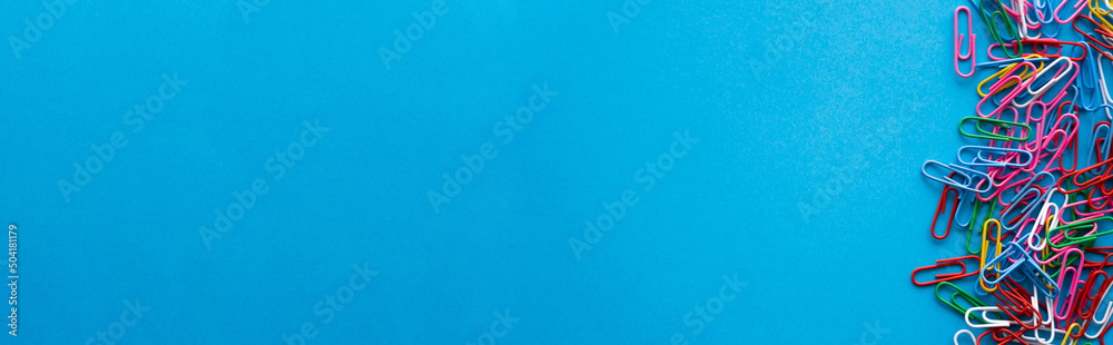 top view of colorful paper clips on blue, banner. - obrazy, fototapety, plakaty 
