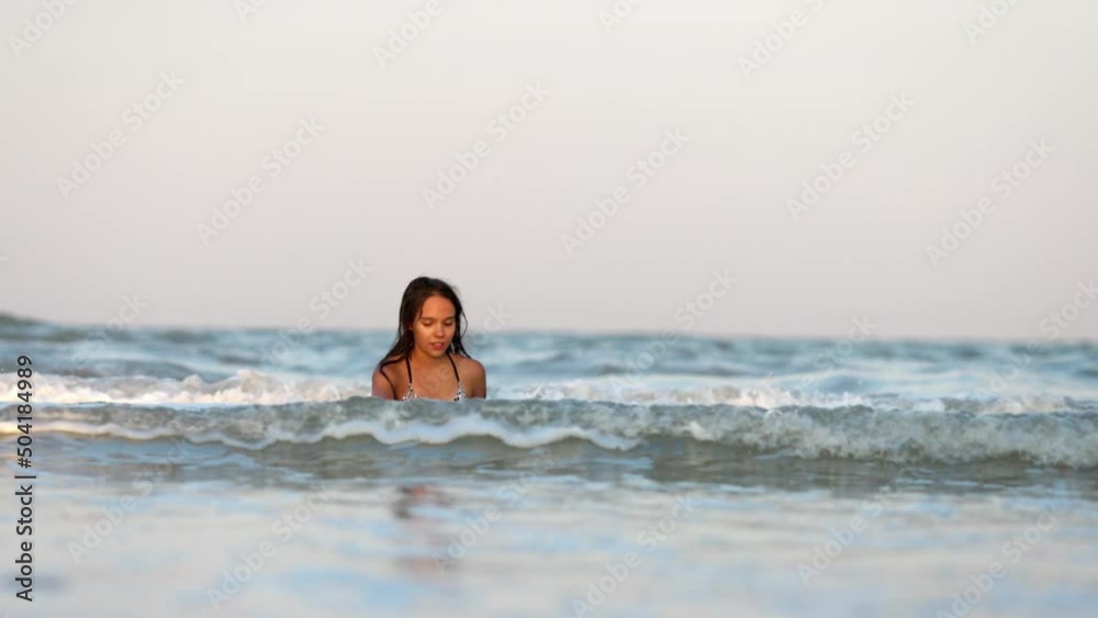 Girl with wet hair in a leopard swimsuit splashes water while sitting in the sea Girl with wet hair in a leopard swimsuit splashes water while sitting in the sea