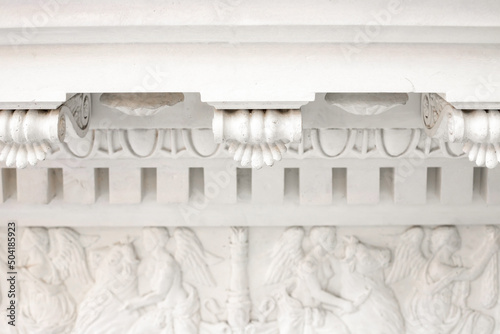 White Cornice and frieze close-up, angels bas-relief. Classic elements of facade decoration, ancient architecture, front view