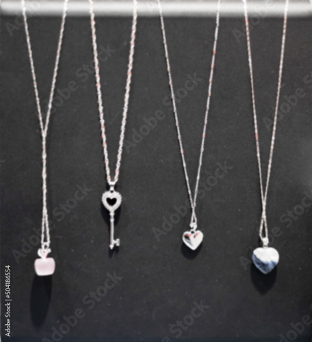 Jewelry pendants on chains hang on a black background. Defocused photo. Precious gift.