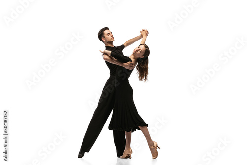 Two young graceful dancers wearing black stage outfits dancing ballroom dance isolated on white background. Concept of art, beauty, music, style. photo