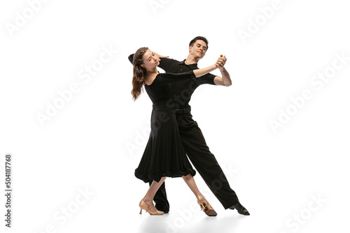 Two young graceful dancers wearing black stage outfits dancing ballroom dance isolated on white background. Concept of art, beauty, music, style.