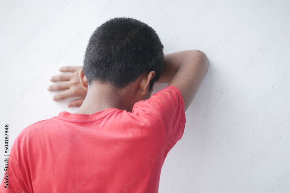 teenage boy head down against white wall teenage boy head down against white wall