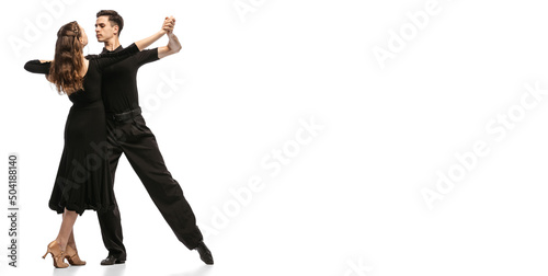 Flyer. Two young graceful dancers wearing black stage outfits dancing ballroom dance isolated on white background. Concept of art, beauty, music, style.