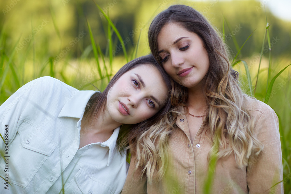 Fototapeta premium Two young women brunette and blonde are standing in a field.