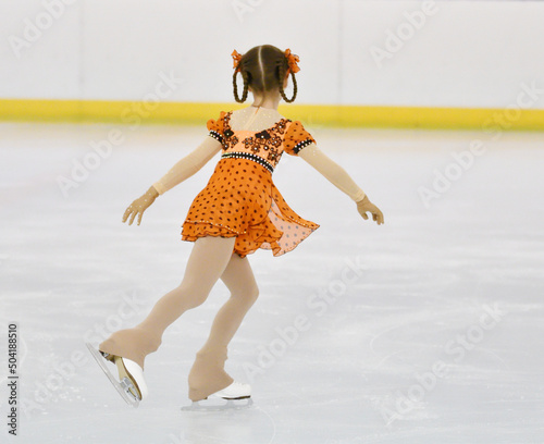 Girl figure skating rolls on a skating rink with artificial ice