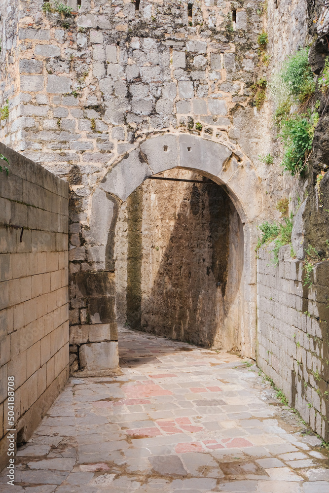 ancient stone arch at the fortress street in the old town at sunny day, light and shadows, historical place