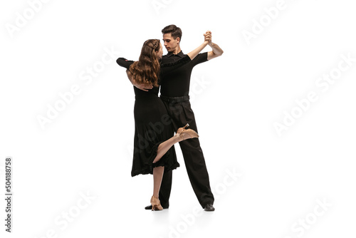 Dynamic portrait of young emotive dancers in black outfits dancing ballroom dance isolated on white background. Concept of art, beauty, music, style.