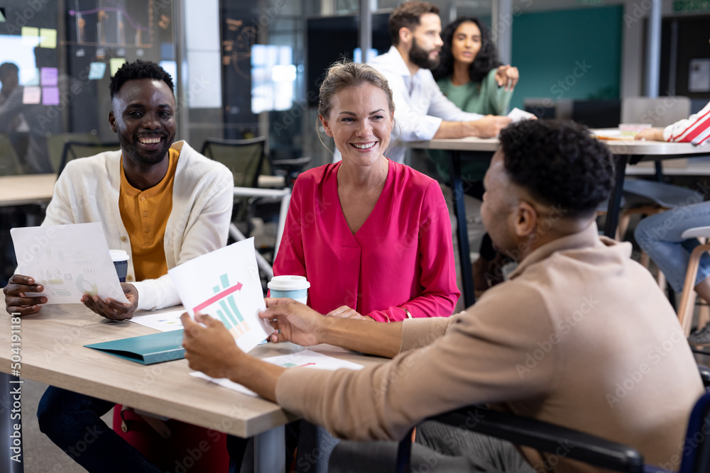 Smiling biracial colleagues discussing over document together in meeting at modern workplace Smiling biracial colleagues discussing over document together in meeting at modern workplace