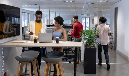 Young african american business advisors working together while standing with laptop at workplace