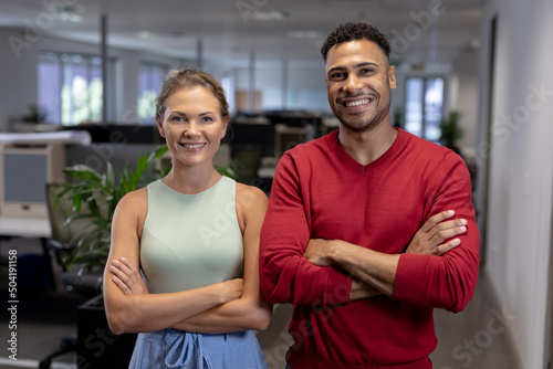 Portrait of smiling multiracial business advisors standing with arms crossed at modern workplace