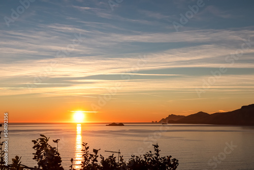 Panoramic sunset view from Praiano at Mediterranean Sea, Italy, Campania, Europe. Silhouette of Li Galli islands and coastline of Amalfi Coast. Reflection of sun beams on water surface during twilight