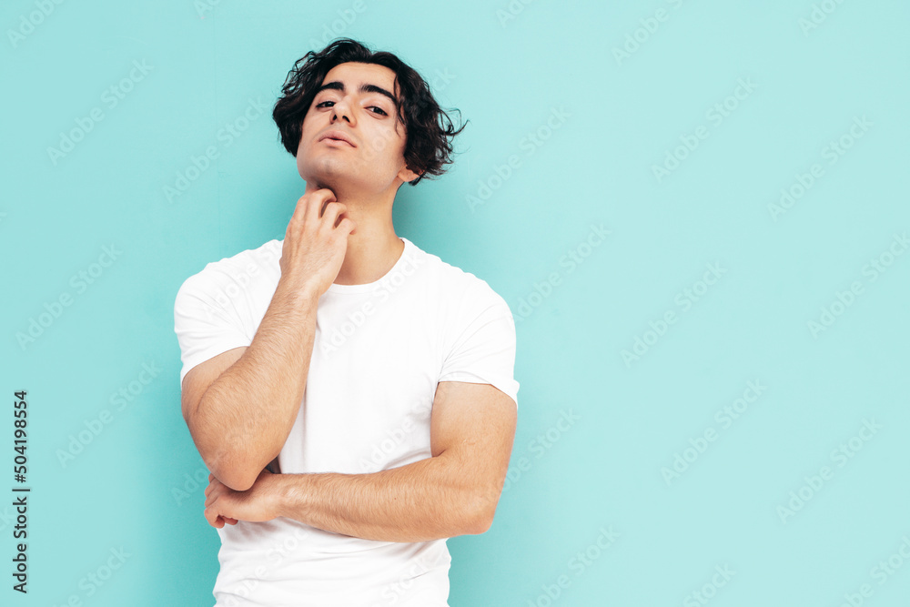 Obraz premium Portrait of handsome confident stylish hipster lambersexual model.Sexy man dressed in summer clothes. Fashion male isolated in studio. Posing near blue wall