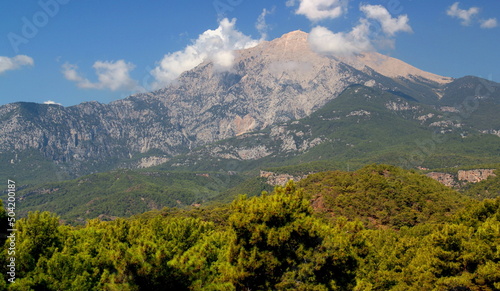 Panoramic view of Tahtalı mountain, which is slightly obscured by clouds, with dense forest in the foreground near the town of Kemer, Antalya region, Turkey 