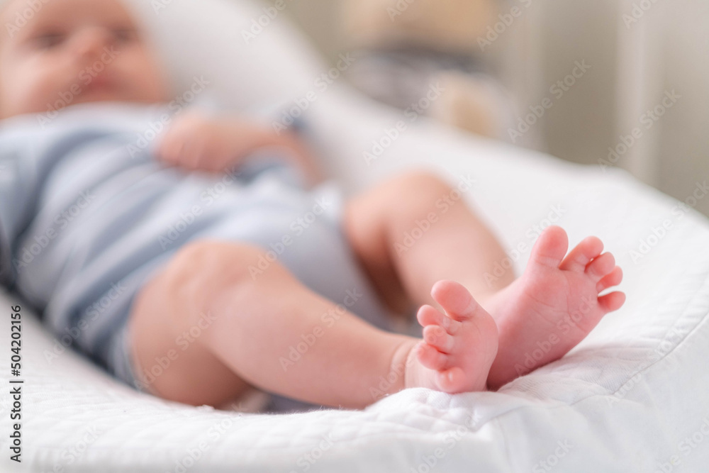Newborn baby boy lying in nursery cocoon with blue clothes on bed in bedroom at home, happy baby morning Newborn baby boy lying in nursery cocoon with blue clothes on bed in bedroom at home, happy baby morning