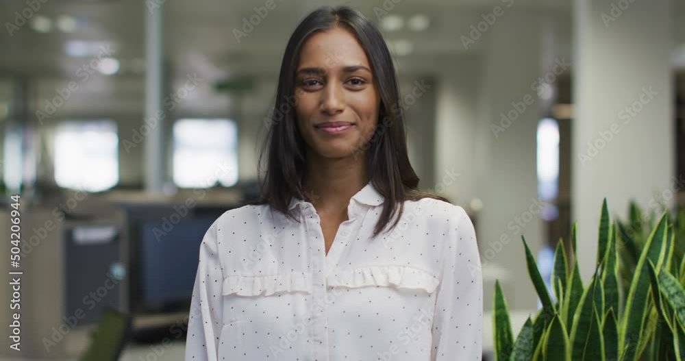Video of happy biracial woman looking at camera in office