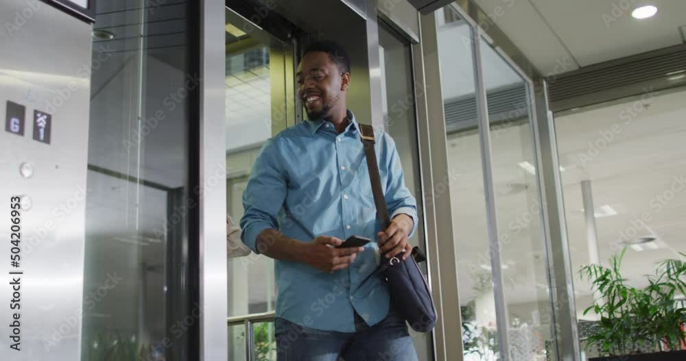 Video of happy diverse woman and man walking outside elevator and talking