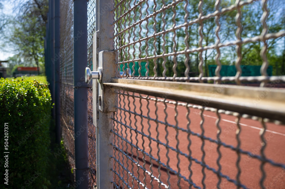 Fototapeta premium Entrance to the sports ground is fenced with a welded wire fence and a gate, on. Concept of a healthy and active lifestyle.
